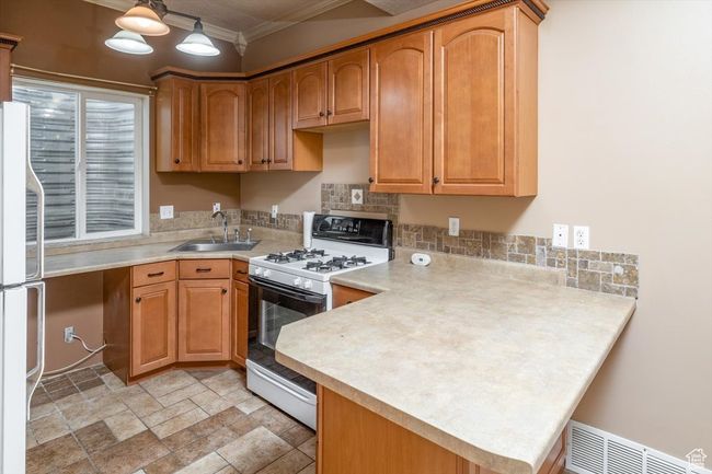 2nd Kitchen featuring kitchen peninsula, crown molding, sink, and white appliances | Image 36