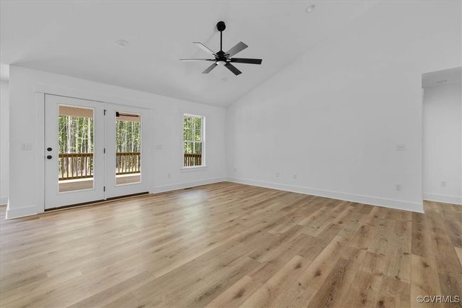 Unfurnished living room featuring light wood finished floors, a healthy amount of sunlight, ceiling fan, and high vaulted ceiling | Image 8