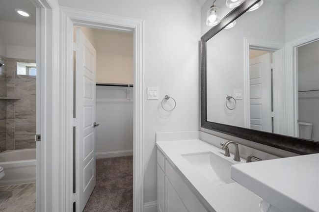 Bathroom with toilet, vanity, a spacious closet, baseboards, and shower / bathtub combination | Image 31