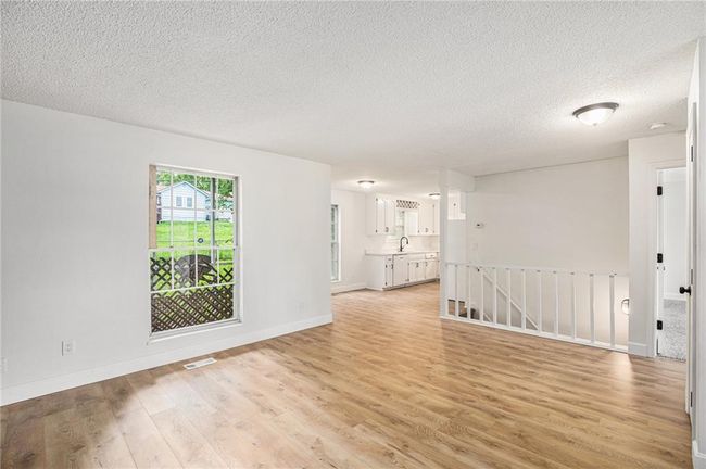 Empty room featuring light wood finished floors, a textured ceiling, a sink, and baseboards | Image 10