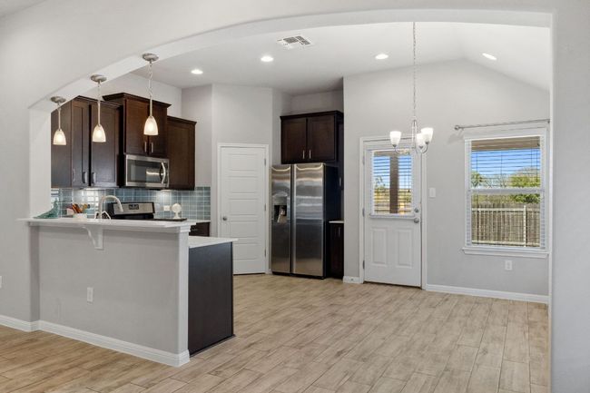 Kitchen featuring espresso cabinetry with upgraded hardware, stainless steel appliances, and pendant lighting | Image 12