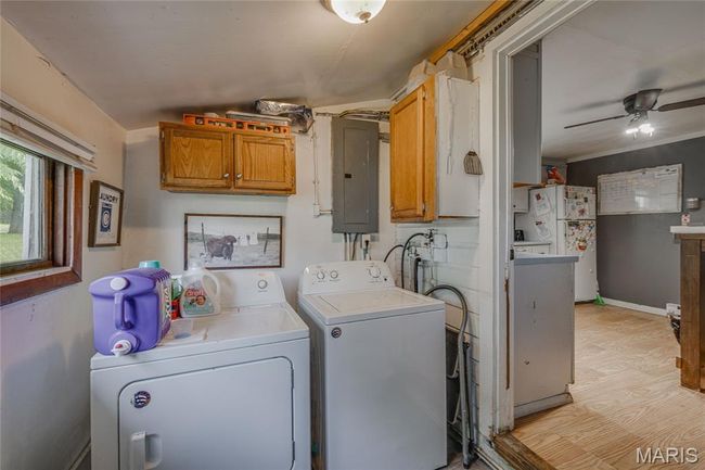 Laundry room featuring electric panel, washer and clothes dryer, ceiling fan, and baseboards | Image 14