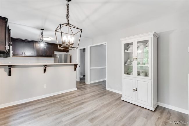 Kitchen with freestanding refrigerator, a breakfast bar area, light countertops, and light wood-style flooring | Image 5