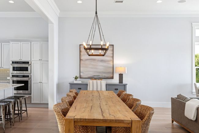 Dining area with baseboards, a chandelier, crown molding, and light wood finished floors | Image 11