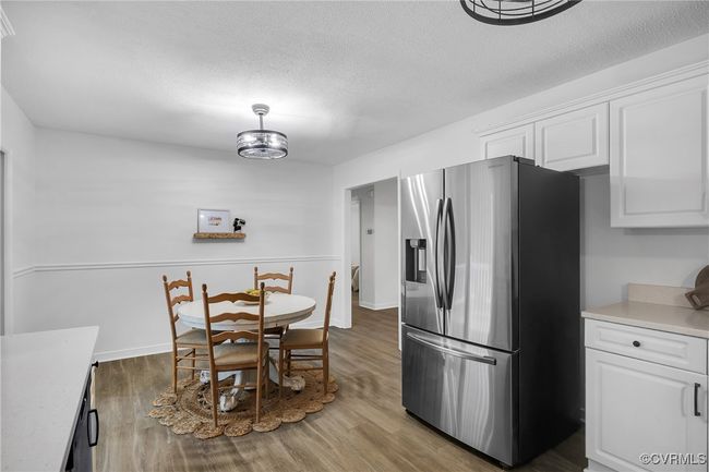 Dining room with wood finished floors, a textured ceiling, and baseboards | Image 9