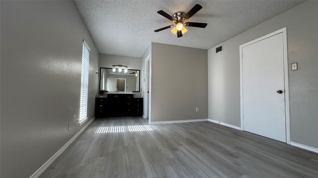Unfurnished bedroom with a textured ceiling, wood finished floors, baseboards, and ceiling fan | Image 8