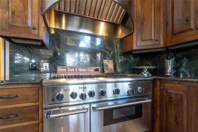 Kitchen with premium range hood, dark stone countertops, tasteful backsplash, and range with two ovens | Image 16