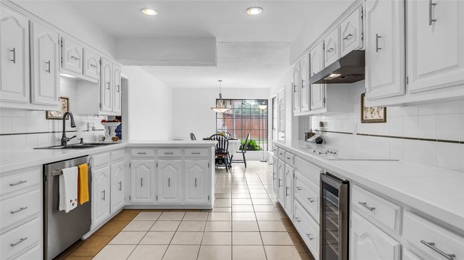 Kitchen with wine cooler, dishwasher, under cabinet range hood, a peninsula, and tasteful backsplash | Image 8