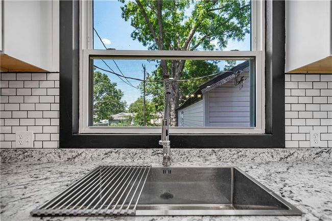 Kitchen view of tasteful backsplash, white cabinetry, light countertops, and a sink | Image 19