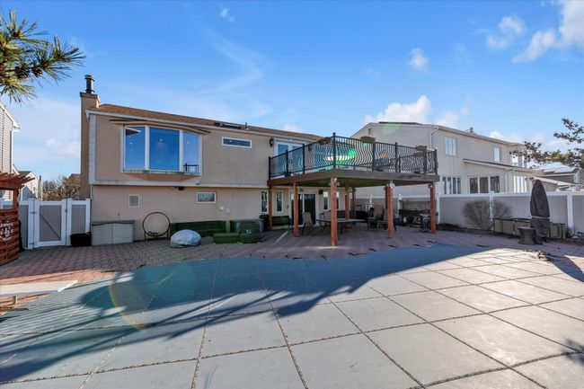 Rear view of property featuring stucco siding, a deck, a gate, a fenced backyard, and a patio area | Image 18