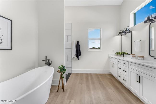 Bathroom with a freestanding tub, wood finished floors, double vanity, and healthy amount of natural light | Image 13