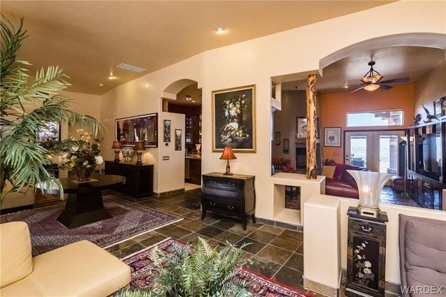 Living room featuring arched walkways, a ceiling fan, and stone tile flooring | Image 30