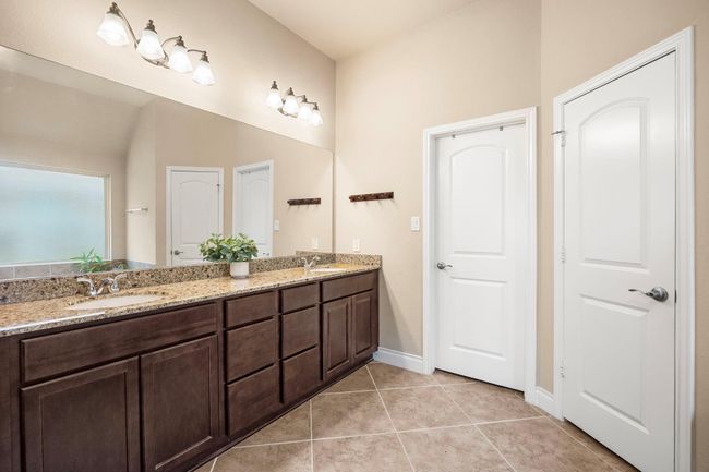 En-suite primary bathroom with double sinks and granite countertops. | Image 19