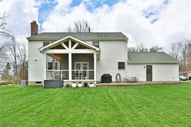Back of house featuring a sunroom, a yard, central air condition unit, and a chimney | Image 5