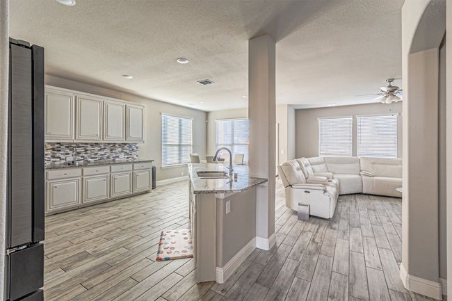 Kitchen featuring a sink, freestanding refrigerator, light wood-style floors, baseboards, and a textured ceiling | Image 9