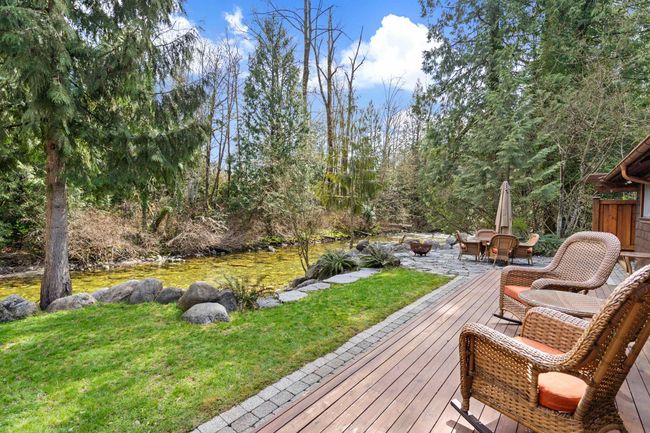 Wooden terrace featuring an outdoor fire pit, a lawn, and a water view | Image 25