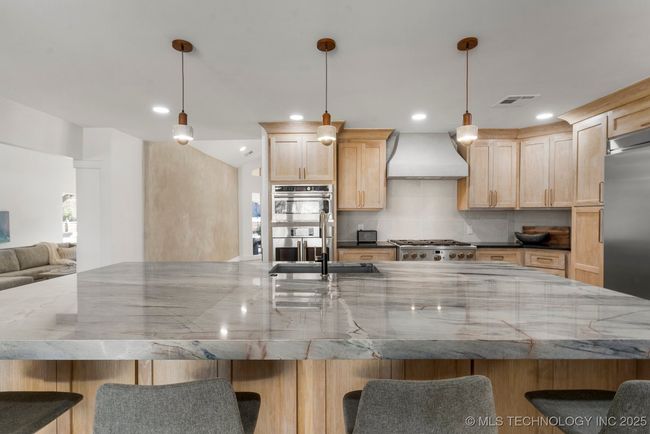 Main kitchen with luxury counters, luxury appliances, bar seating, and custom cabinets | Image 24