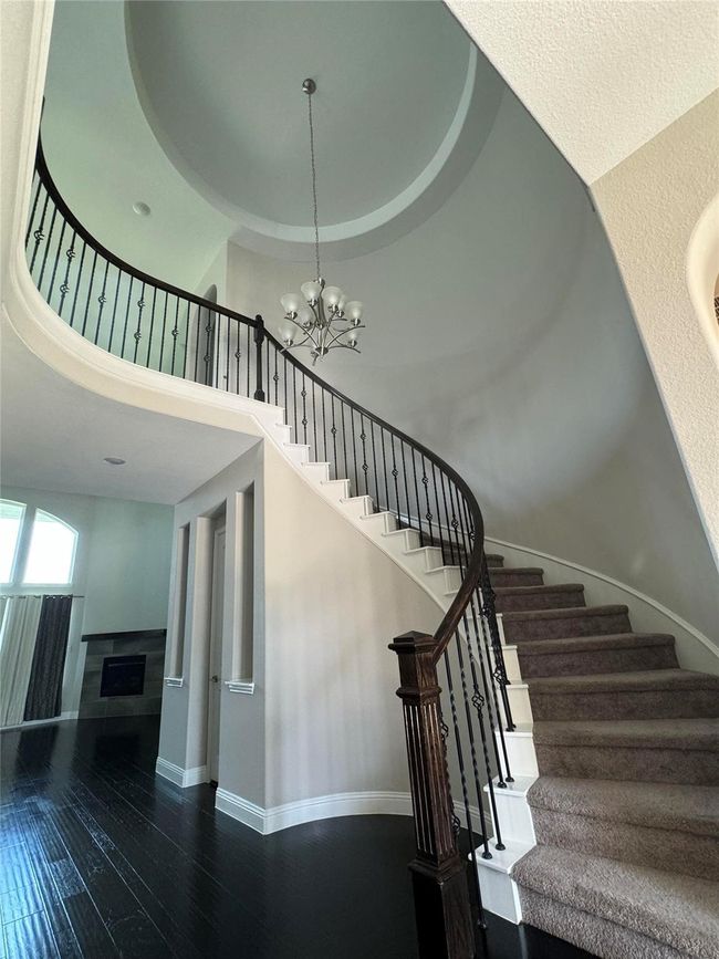 Stairs with a chandelier, wood-type flooring, a high ceiling, and a fireplace | Image 32