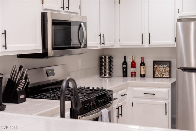 Kitchen with appliances with stainless steel finishes, white cabinets, and tile countertops | Image 15