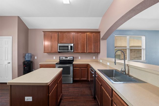 Kitchen with appliances with stainless steel finishes, lofted ceiling, light countertops, dark wood finished floors, and a sink | Image 22