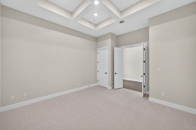 Unfurnished bedroom featuring coffered ceiling, light colored carpet, and beamed ceiling | Image 16