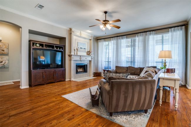 Large living room with fireplace, crown molding, & wood finished floors | Image 9