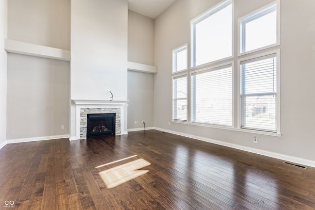unfurnished living room featuring baseboards, a stone fireplace, visible vents, and dark wood-type flooring | Image 13