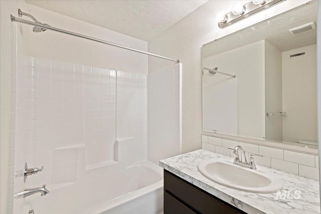 Full bathroom featuring shower / tub combination, vanity, a textured ceiling, and a textured wall | Image 14