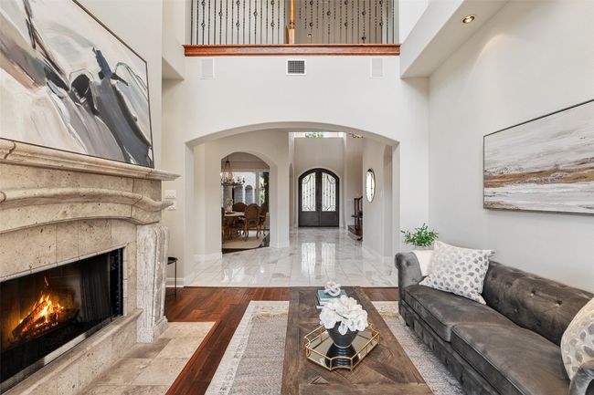 Living area with arched walkways, a premium fireplace, baseboards, and a towering ceiling | Image 10
