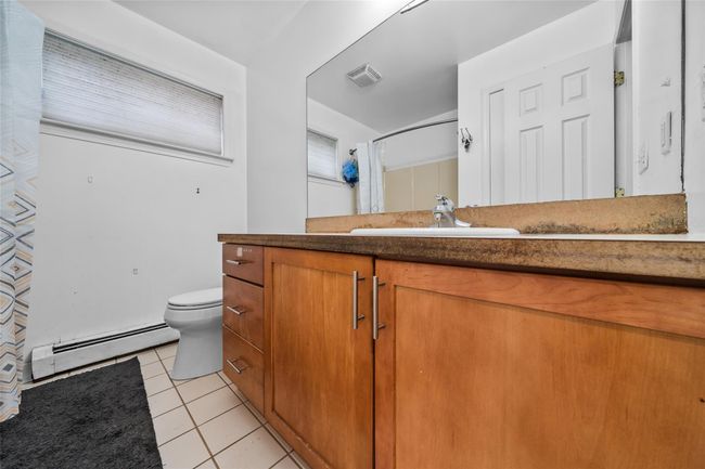 Full bathroom featuring vanity, tile patterned flooring, toilet, visible vents, and a baseboard radiator | Image 33