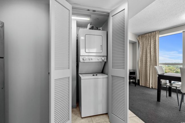 Washroom with laundry area, light tile patterned floors, a textured ceiling, light colored carpet, and stacked washer / dryer | Image 28