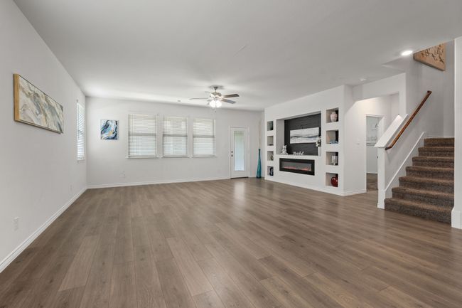 Living room featuring built in shelves, ceiling fan, stairs, dark wood-style floors, and baseboards | Image 13