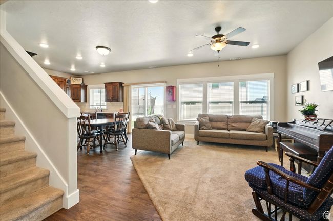 Living area with a ceiling fan, wood finished floors, stairway, and recessed lighting | Image 5