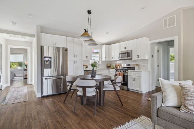 Kitchen with appliances with stainless steel finishes, lofted ceiling, white cabinets, decorative backsplash, and dark wood-style flooring | Image 11