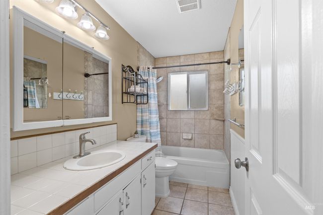 Full bath with shower / tub combo, vanity, tasteful backsplash, and tile patterned floors | Image 17