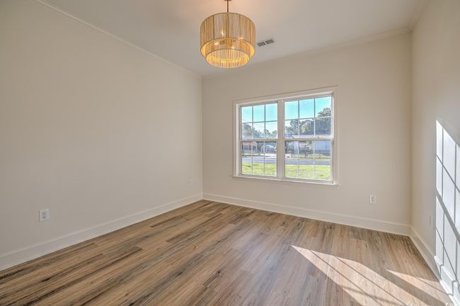 Empty room featuring wood finished floors, ornamental molding, and a chandelier | Image 20