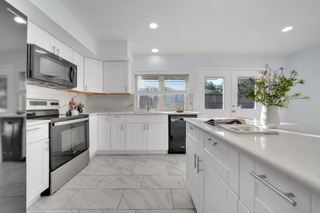 Kitchen featuring black appliances, light marble finish floors, light countertops, recessed lighting, and white cabinetry | Image 29