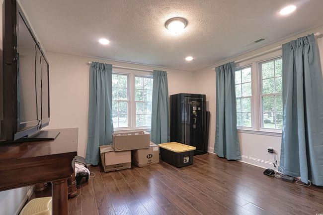 Bedroom featuring dark wood-style flooring, multiple windows, a textured ceiling, and recessed lighting | Image 24