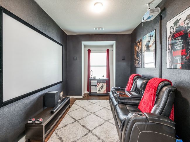 Cinema featuring a textured wall, wood finished floors, visible vents, and baseboards | Image 6