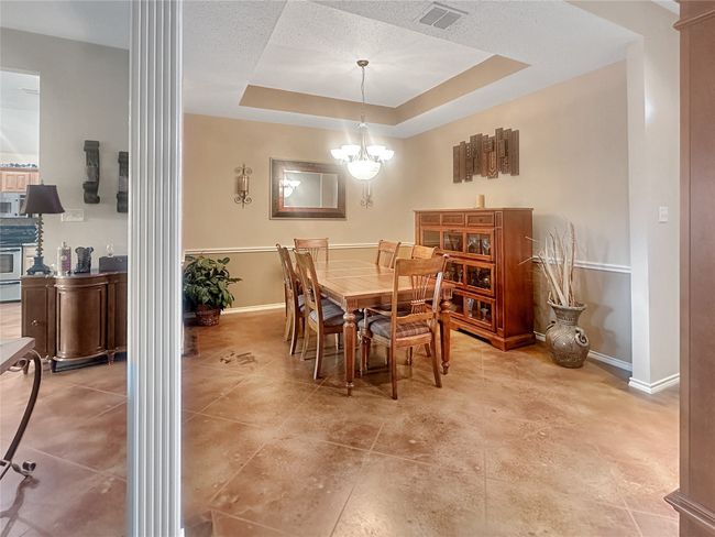 Dining space featuring baseboards, a chandelier, and a raised ceiling | Image 4