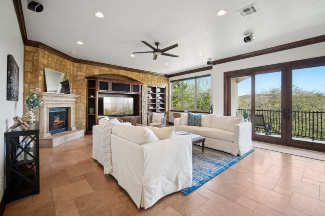 Living area with visible vents, a ceiling fan, a glass covered fireplace, recessed lighting, and crown molding | Image 9