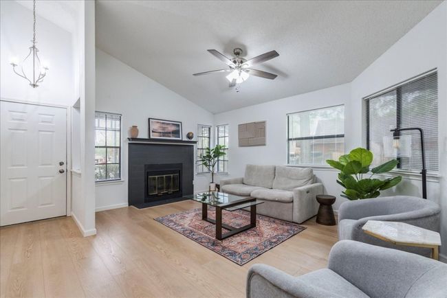 Living room featuring a fireplace with flush hearth, baseboards, light wood-style floors, and a ceiling fan | Image 6