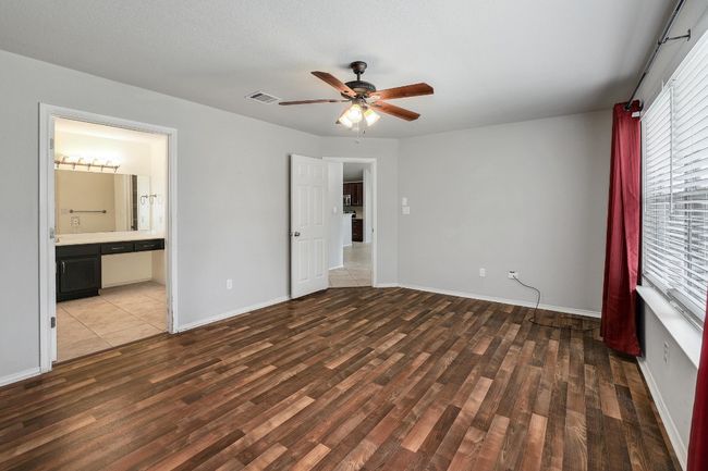 Unfurnished bedroom featuring wood finished floors, a ceiling fan, and ensuite bathroom | Image 16