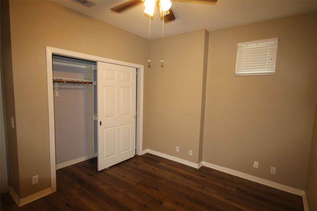 Unfurnished bedroom with dark wood-style floors, a closet, and ceiling fan | Image 9