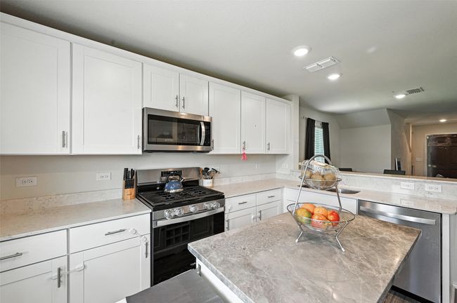 Kitchen with stainless steel appliances, a peninsula, white cabinetry, a kitchen island, and recessed lighting | Image 10