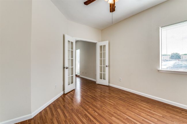 Spare room featuring baseboards, wood finished floors, french doors, and a ceiling fan | Image 13