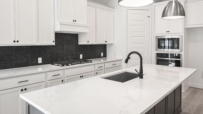 Kitchen with backsplash, white cabinets, appliances with stainless steel finishes, and light stone counters | Image 8