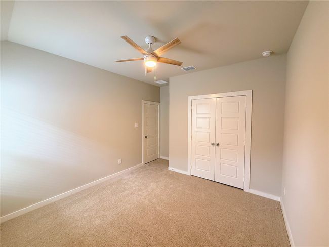 Unfurnished bedroom featuring light colored carpet, baseboards, a closet, and a ceiling fan | Image 23