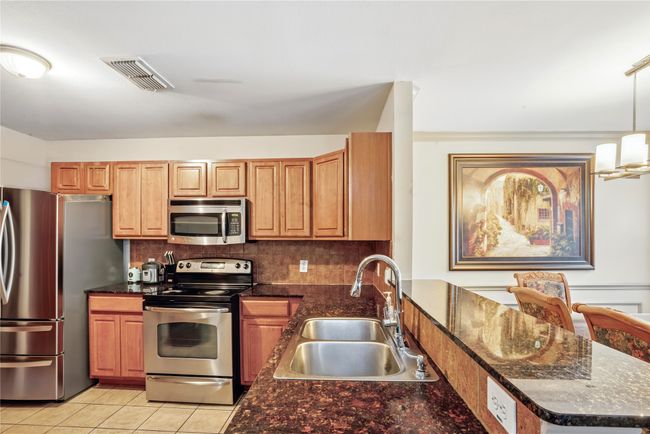 Kitchen featuring appliances with stainless steel finishes, tasteful backsplash, light tile patterned flooring, a peninsula, and decorative light​​‌​​​​‌​​‌‌​‌‌​​​‌‌​​‌‌​‌​​​​​‌ fixtures | Image 13