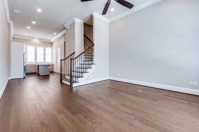 Unfurnished living room with ornamental molding, dark wood finished floors, a ceiling fan, stairway, and recessed lighting | Image 13